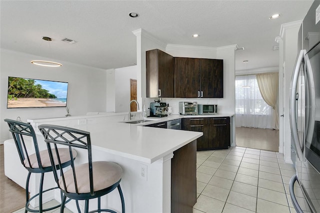 17300 Summer Sun Ct, Clermont, FL 34711 - kitchen with a peninsula, dark brown cabinetry, light countertops, a kitchen bar, and stainless steel appliances