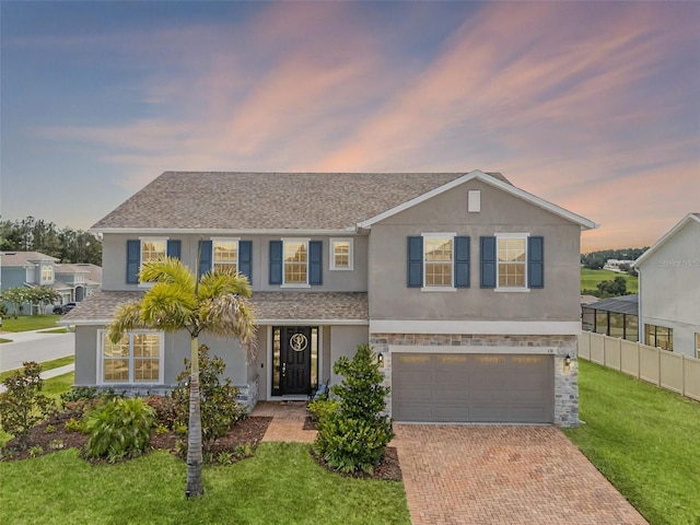 391 Cheeota Ct, Minneola, FL 34715 - traditional home with stucco siding, decorative driveway, a front yard, an attached garage, and a shingled roof