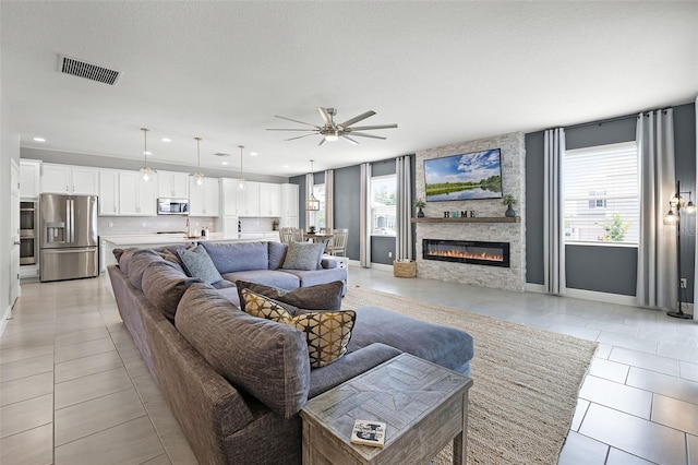 391 Cheeota Ct, Minneola, FL 34715 - living area with plenty of natural light, a ceiling fan, light tile patterned floors, a stone fireplace, and recessed lighting