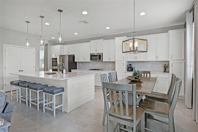 391 Cheeota Ct, Minneola, FL 34715 - kitchen featuring stainless steel appliances, tasteful backsplash, an island with sink, white cabinets, and recessed lighting