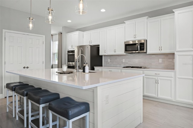 391 Cheeota Ct, Minneola, FL 34715 - kitchen with appliances with stainless steel finishes, decorative backsplash, a center island with sink, white cabinets, and recessed lighting