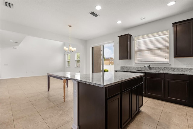 752 Sandy Bar Dr, Winter Garden, FL 34787 - kitchen featuring a chandelier, light stone countertops, a center island, recessed lighting, and dark brown cabinetry