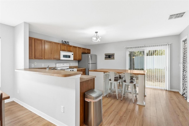 2336 Martins Run, Tavares, FL 32778 - kitchen featuring white appliances, brown cabinetry, light wood-style floors, and light countertops