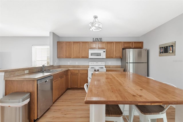 2336 Martins Run, Tavares, FL 32778 - kitchen with appliances with stainless steel finishes, light wood-style flooring, a peninsula, a chandelier, and brown cabinetry