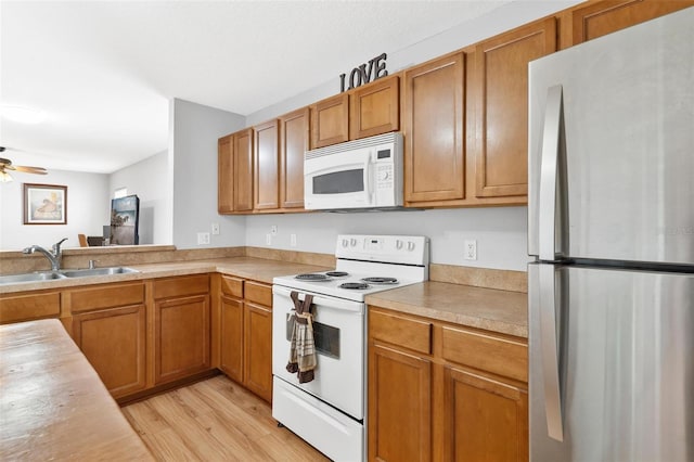 2336 Martins Run, Tavares, FL 32778 - kitchen with white appliances, light wood-style floors, light countertops, and brown cabinets