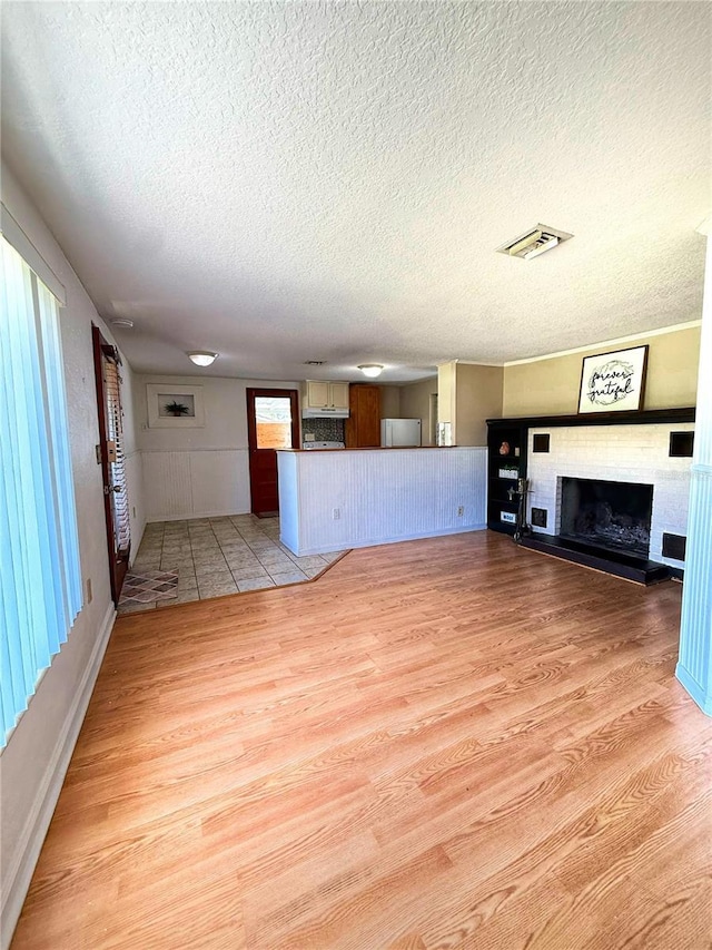 100 W Idlewild Ave, Eustis, FL 32726 - unfurnished living room with light wood-style flooring, a fireplace with raised hearth, and a textured ceiling