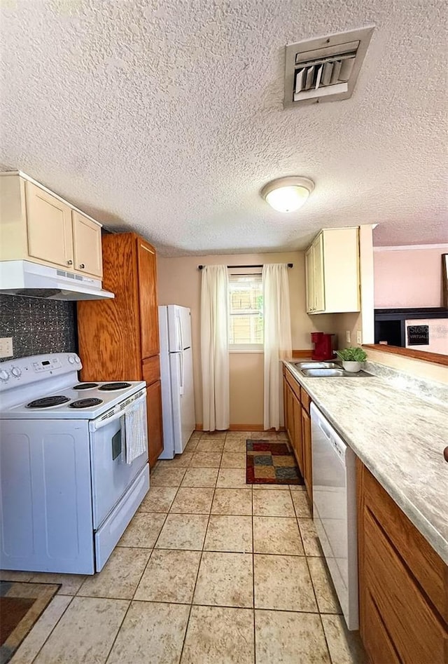 100 W Idlewild Ave, Eustis, FL 32726 - kitchen with white appliances, under cabinet range hood, light countertops, light tile patterned floors, and a textured ceiling