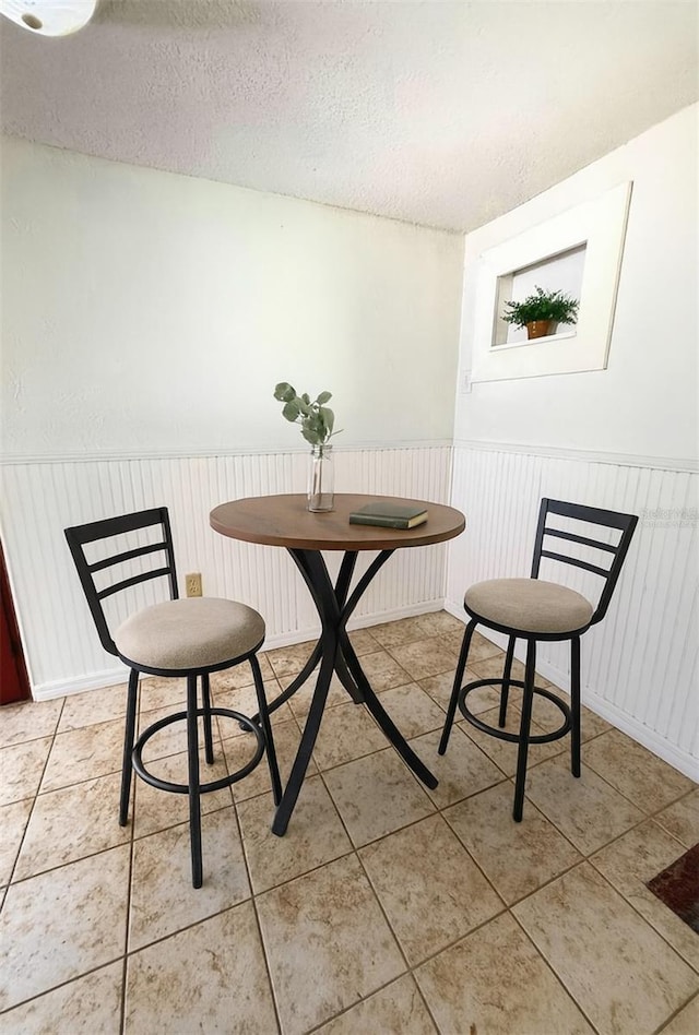 100 W Idlewild Ave, Eustis, FL 32726 - dining space with wainscoting, a textured ceiling, and light tile patterned floors
