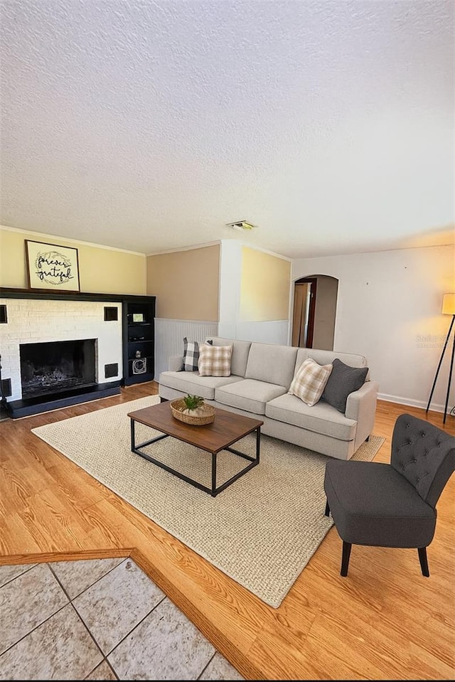 100 W Idlewild Ave, Eustis, FL 32726 - living area with a textured ceiling, a fireplace with raised hearth, a wainscoted wall, wood finished floors, and arched walkways