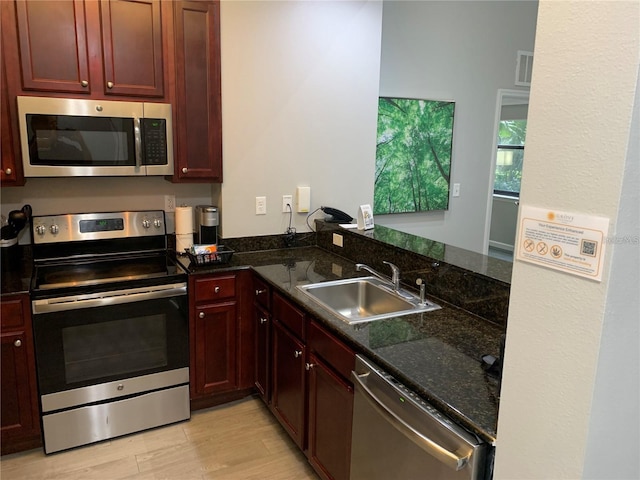14501 Grove Resort Ave Unit 3406, Winter Garden, FL 34787 - kitchen featuring appliances with stainless steel finishes, a sink, light wood-style flooring, dark brown cabinets, and dark stone countertops