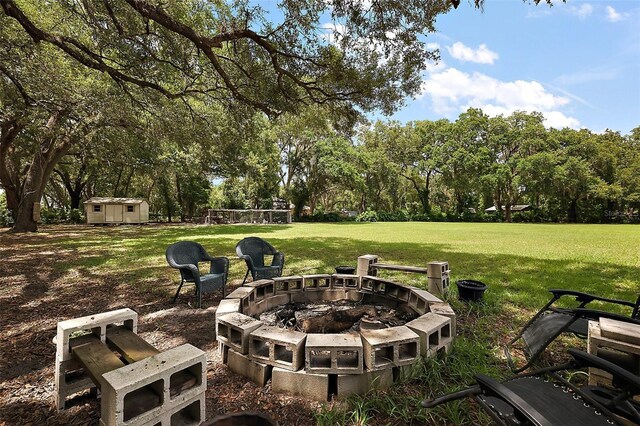 672 E Belt Ave, Bushnell, FL 33513 - view of grassy yard featuring an outdoor fire pit and view of wooded area