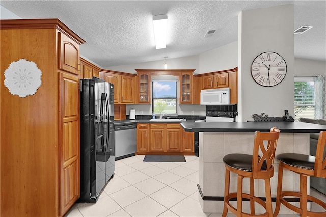 1815 Kaufman Cir, Lady Lake, FL 32159 - kitchen featuring black appliances, lofted ceiling, a breakfast bar area, glass insert cabinets, and dark countertops