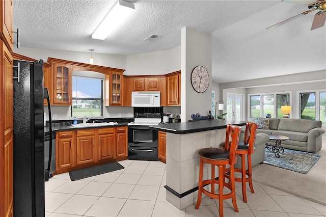 1815 Kaufman Cir, Lady Lake, FL 32159 - kitchen with electric range, white microwave, freestanding refrigerator, open floor plan, and a peninsula
