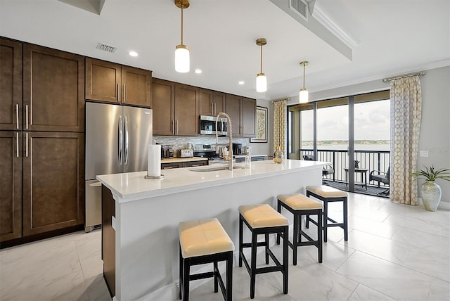 16300 County Road 455 Unit 202, Montverde, FL 34756 - kitchen featuring appliances with stainless steel finishes, light marble finish floors, a kitchen breakfast bar, a sink, and light countertops
