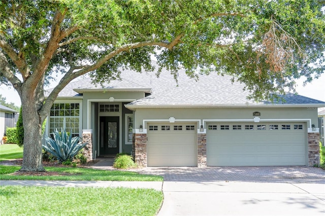 1355 Misty Glen Ln, Clermont, FL 34711 - view of front of home featuring stone siding, a garage, decorative driveway, stucco siding, and roof with shingles