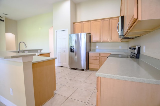 1355 Misty Glen Ln, Clermont, FL 34711 - kitchen featuring appliances with stainless steel finishes, arched walkways, light brown cabinetry, and light tile patterned flooring