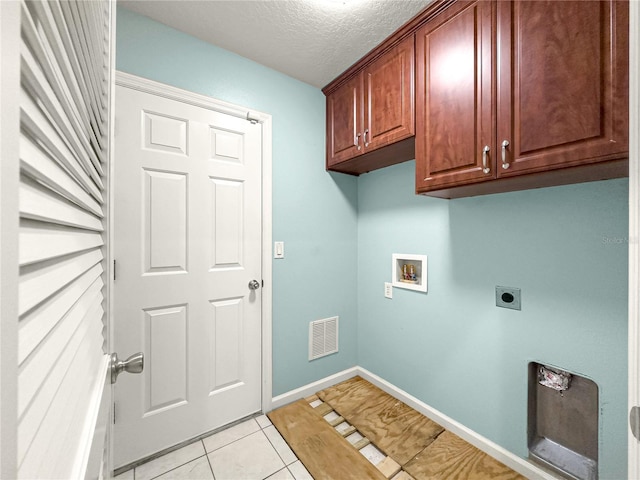 8045 Waterbury Way, Mount Dora, FL 32757 - laundry area featuring hookup for an electric dryer, washer hookup, cabinet space, a textured ceiling, and light tile patterned flooring