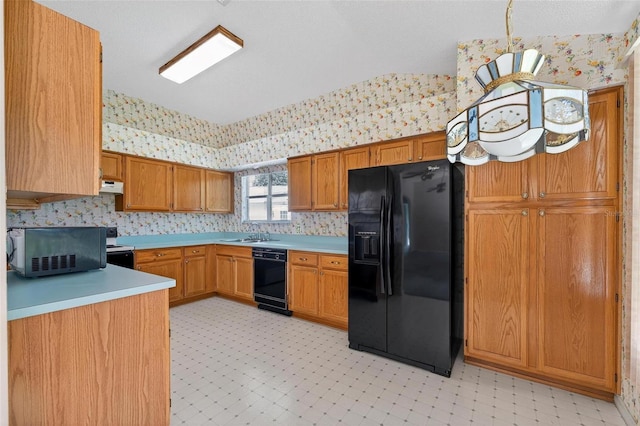 206 Palermo Pl, Lady Lake, FL 32159 - kitchen with black appliances, wallpapered walls, under cabinet range hood, light countertops, and brown cabinetry