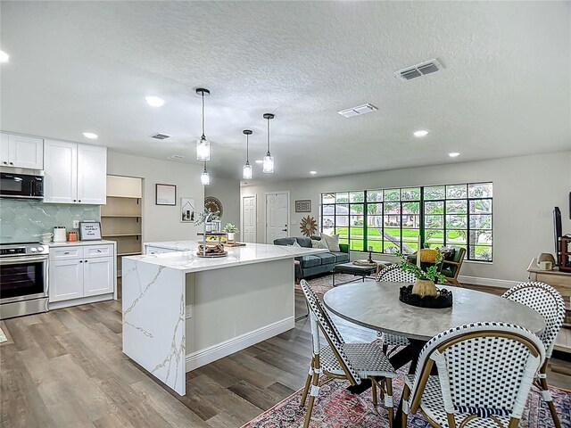 1611 Canal, Tavares, FL 32778 - kitchen featuring stainless steel appliances, wood finished floors, recessed lighting, white cabinets, and light stone countertops