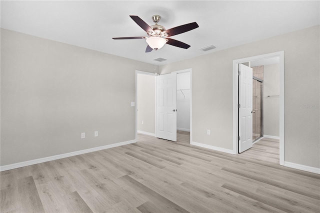 14631 SE 95th Ct, Summerfield, FL 34491 - unfurnished bedroom featuring light wood-style flooring, a walk in closet, a closet, ensuite bath, and a ceiling fan