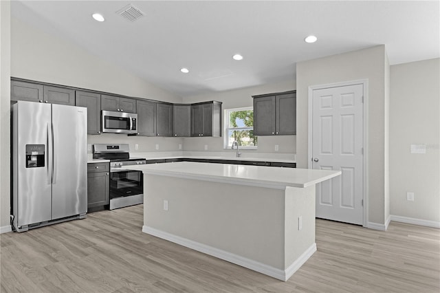 14611 SE 95th Ct, Summerfield, FL 34491 - kitchen featuring stainless steel appliances, a center island, light countertops, light wood-type flooring, and vaulted ceiling