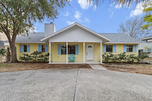 11770 W Sunnybrook Ct, Crystal River, FL 34429 - ranch-style house featuring a chimney, a porch, brick siding, and driveway