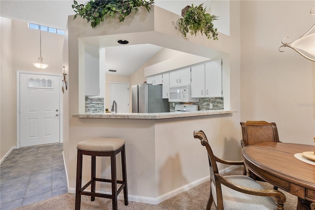 5512 Rosewall Cir, Leesburg, FL 34748 - kitchen with freestanding refrigerator, white microwave, decorative backsplash, a kitchen bar, and vaulted ceiling