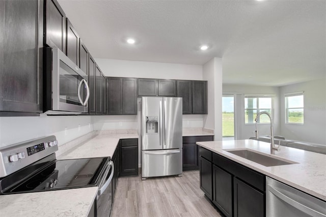 1696 Wilson Prairie Cir, Groveland, FL 34736 - kitchen featuring stainless steel appliances, recessed lighting, light wood finished floors, light stone countertops, and a textured ceiling
