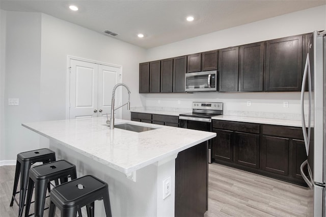 1696 Wilson Prairie Cir, Groveland, FL 34736 - kitchen featuring stainless steel appliances, an island with sink, a kitchen breakfast bar, recessed lighting, and light wood-style flooring