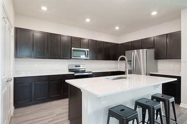 1696 Wilson Prairie Cir, Groveland, FL 34736 - kitchen featuring stainless steel appliances, a kitchen bar, light wood-style flooring, an island with sink, and recessed lighting