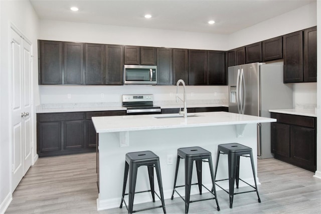 1696 Wilson Prairie Cir, Groveland, FL 34736 - kitchen featuring stainless steel microwave, electric stove, a kitchen bar, light wood-style floors, and light countertops