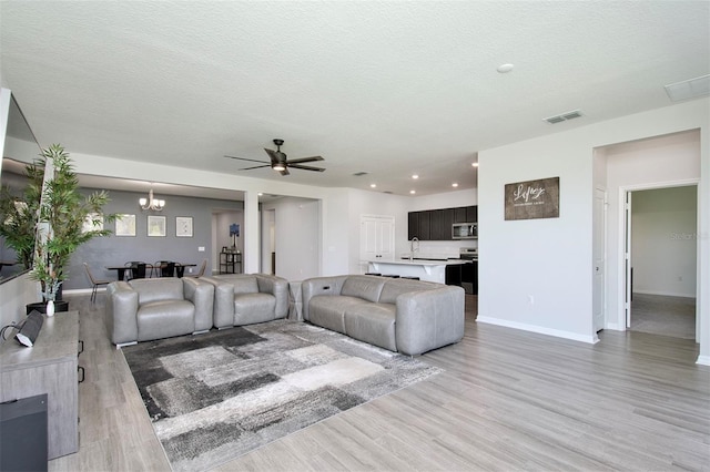 1696 Wilson Prairie Cir, Groveland, FL 34736 - living area featuring light wood finished floors, ceiling fan, a chandelier, recessed lighting, and a textured ceiling