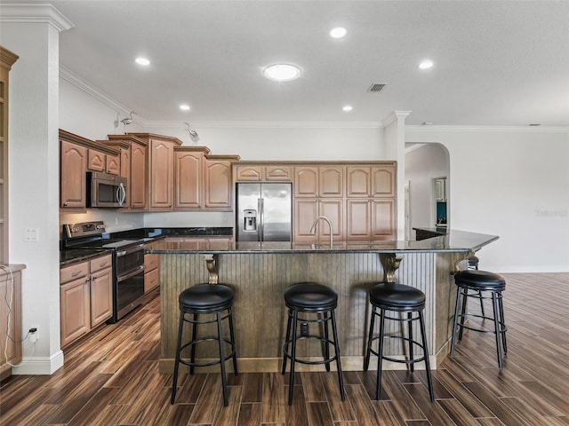 12198 SE 176th Loop, Summerfield, FL 34491 - kitchen featuring appliances with stainless steel finishes, wood finish floors, dark countertops, arched walkways, and ornamental molding