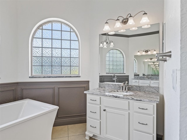 12198 SE 176th Loop, Summerfield, FL 34491 - bathroom featuring a soaking tub, healthy amount of natural light, tile patterned floors, vanity, and wainscoting