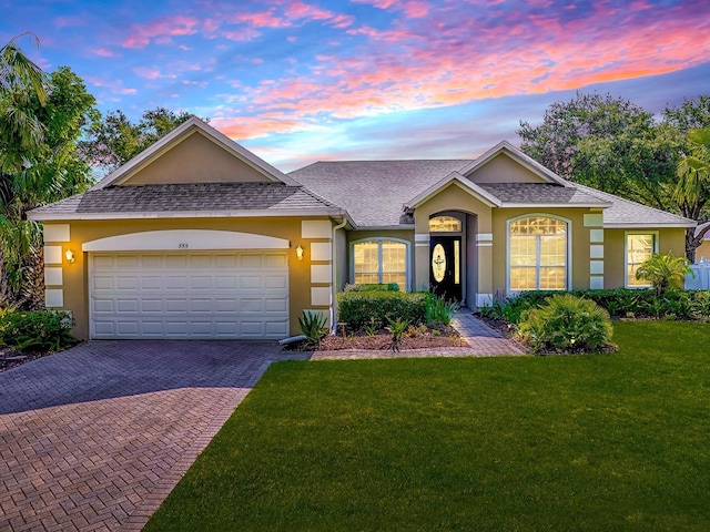 359 Blue Branch St, Eustis, FL 32736 - ranch-style house featuring stucco siding, decorative driveway, a garage, a yard, and roof with shingles