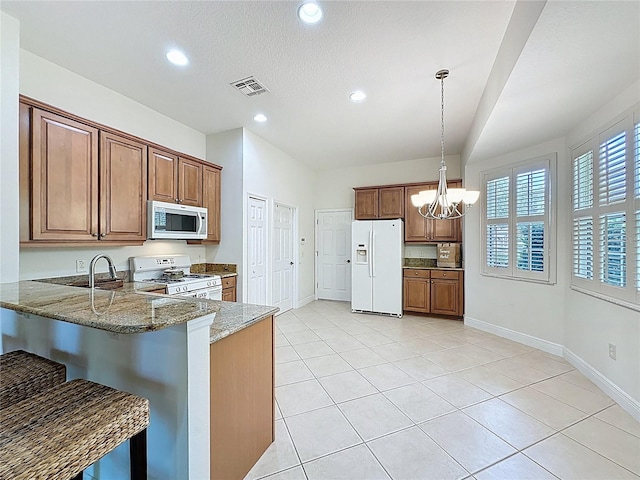 101 Flame Vine Way, Groveland, FL 34736 - kitchen with white appliances, light stone countertops, a peninsula, a chandelier, and recessed lighting