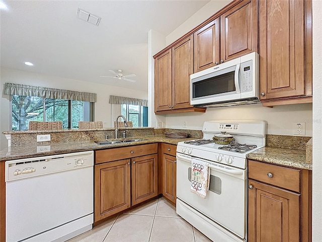 101 Flame Vine Way, Groveland, FL 34736 - kitchen with white appliances, brown cabinetry, and stone countertops