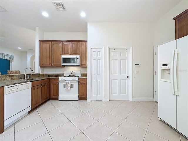 101 Flame Vine Way, Groveland, FL 34736 - kitchen with white appliances, light tile patterned flooring, brown cabinets, dark stone counters, and recessed lighting