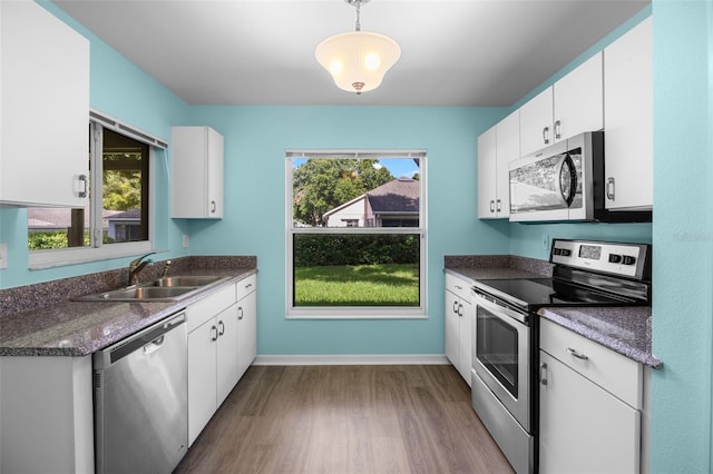 3586 Eversholt St, Clermont, FL 34711 - kitchen featuring stainless steel appliances, dark wood-style flooring, dark countertops, white cabinets, and hanging light fixtures