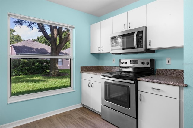 3586 Eversholt St, Clermont, FL 34711 - kitchen with stainless steel appliances, wood finished floors, dark countertops, and white cabinets