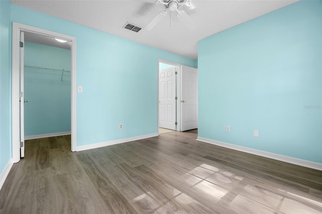 3586 Eversholt St, Clermont, FL 34711 - unfurnished bedroom featuring a spacious closet, wood finished floors, a closet, and a ceiling fan