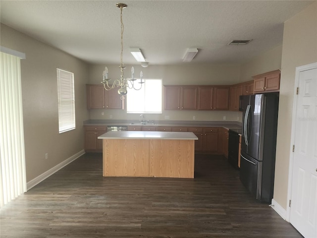 222 Bacopa Pass, Davenport, FL 33897 - kitchen featuring freestanding refrigerator, a kitchen island, a chandelier, dark wood-style flooring, and a textured ceiling