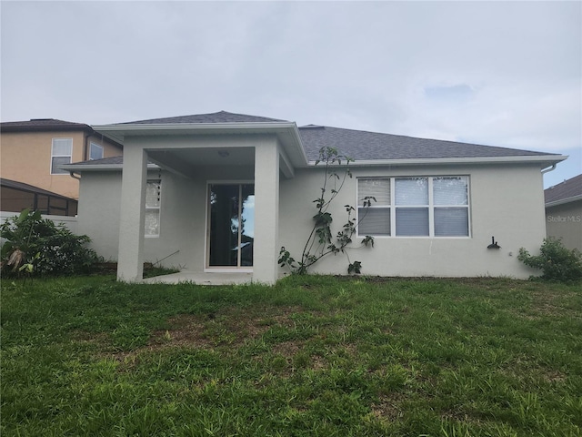 222 Bacopa Pass, Davenport, FL 33897 - rear view of property with stucco siding, a lawn, and roof with shingles
