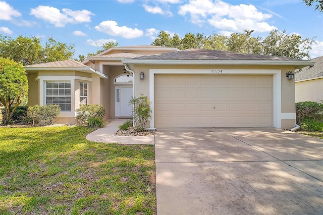 33234 Kaylee Way, Leesburg, FL 34788 - view of front facade featuring stucco siding, driveway, an attached garage, and a front lawn