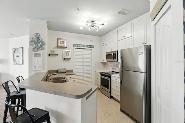 2639 Maitland Crossing Way Unit 102, Orlando, FL 32810 - kitchen featuring appliances with stainless steel finishes, a peninsula, a breakfast bar, decorative backsplash, and light tile patterned floors