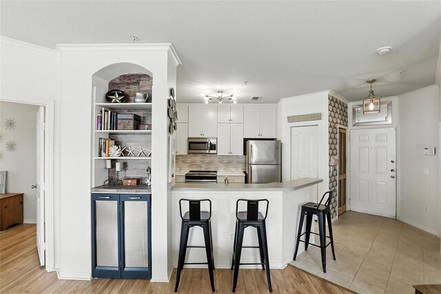 2639 Maitland Crossing Way Unit 102, Orlando, FL 32810 - kitchen with appliances with stainless steel finishes, a breakfast bar area, a peninsula, tasteful backsplash, and white cabinetry