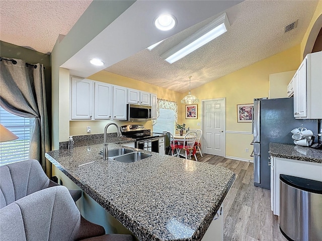 3716 Eversholt St, Clermont, FL 34711 - kitchen with stainless steel appliances, vaulted ceiling, a textured ceiling, a peninsula, and white cabinets