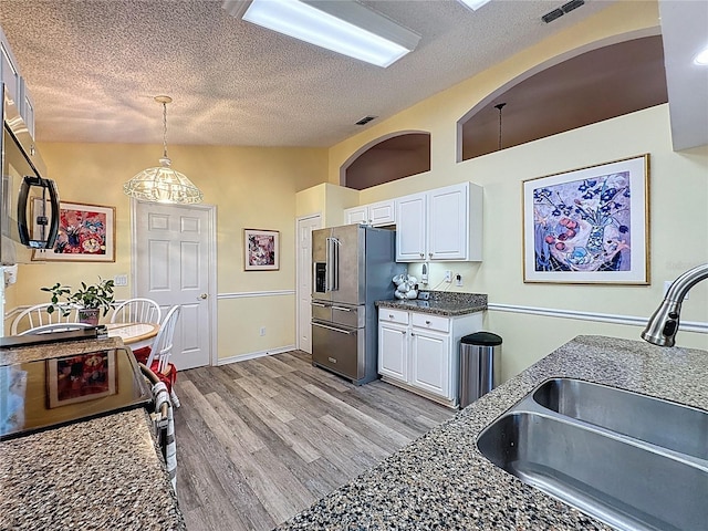3716 Eversholt St, Clermont, FL 34711 - kitchen featuring appliances with stainless steel finishes, a textured ceiling, white cabinets, light wood-style flooring, and vaulted ceiling