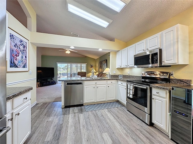 3716 Eversholt St, Clermont, FL 34711 - kitchen featuring appliances with stainless steel finishes, beverage cooler, vaulted ceiling, light wood-type flooring, and open floor plan