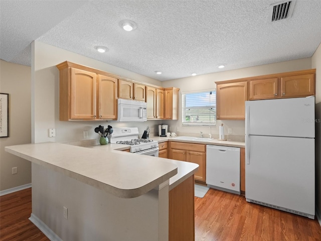 2369 Five Forks Trl, The Villages, FL 32162 - kitchen featuring white appliances, a peninsula, a textured ceiling, light countertops, and light wood finished floors